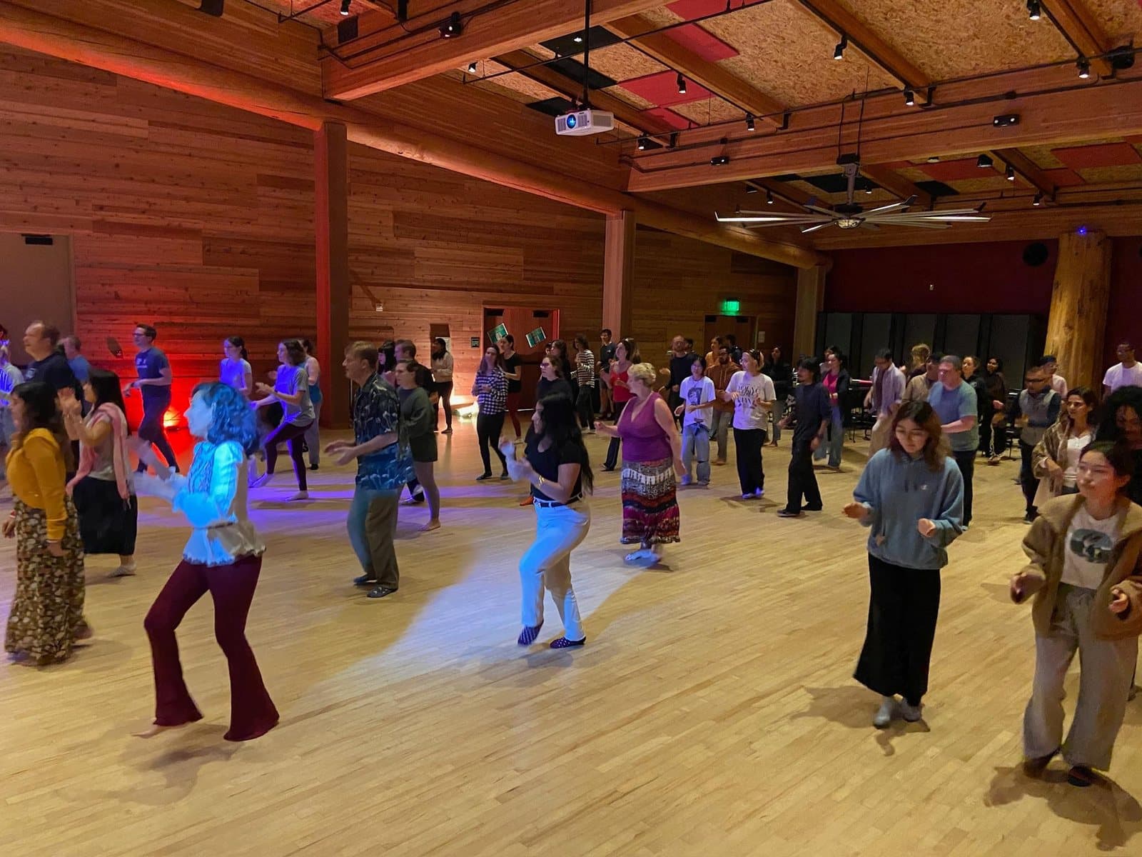 A large group dancing together in a wood-paneled hall at the University of Washington