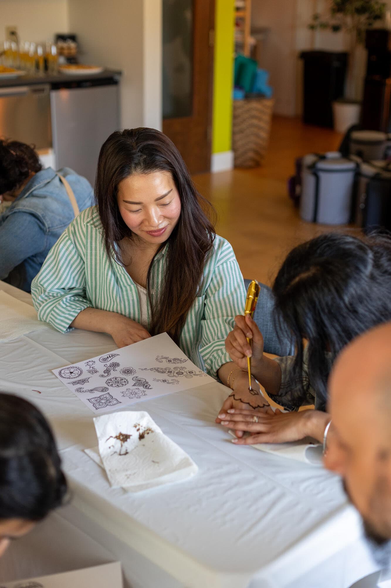 Guests practicing mehndi (henna) patterns on paper and on a hand